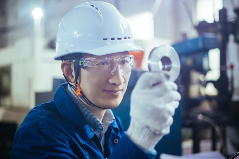 An Asian engineer in the factory uses a digital tablet to check inventory and ensure quality control