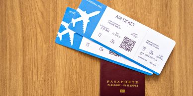 Passport with two airplane tickets on a wooden surface.