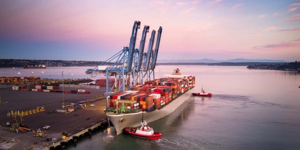 Cargo ship docked at port during sunset.