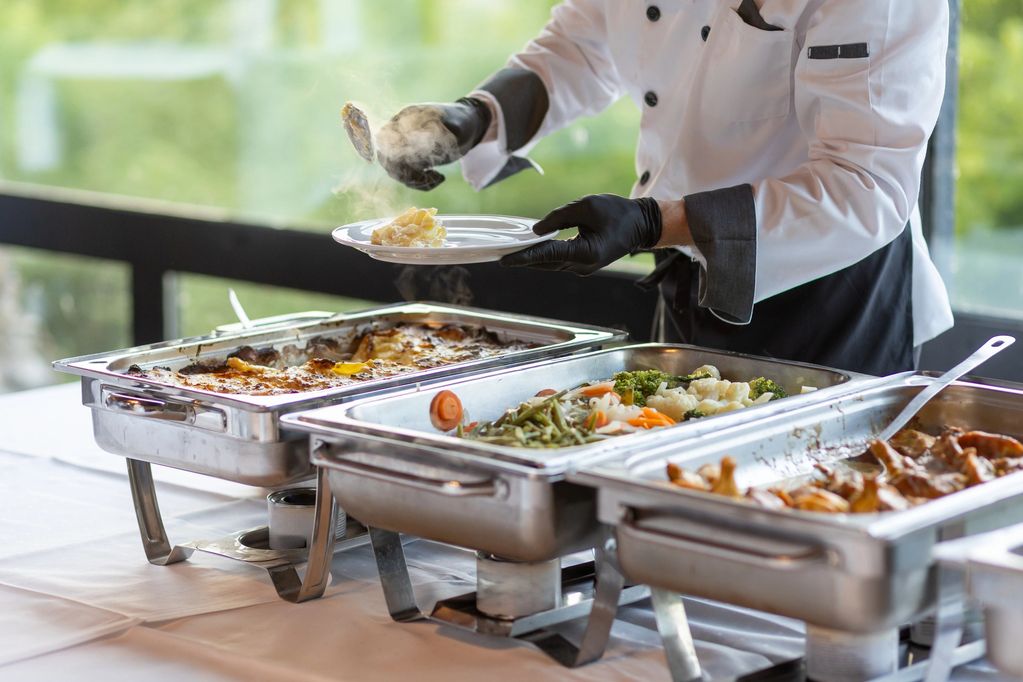 Chef serving food from buffet trays.
