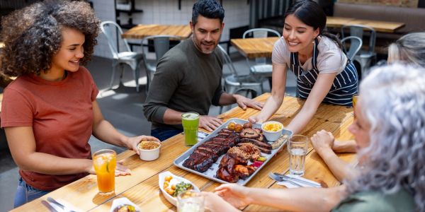 People enjoying a meal with ribs and sides at a restaurant.