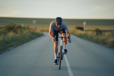 Cyclist riding on an open road at sunset.
