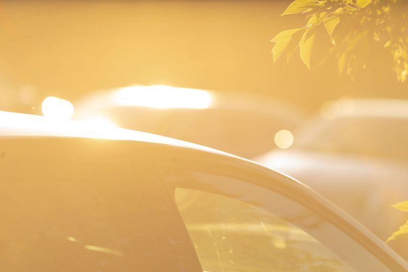A beautifully sunlit scene vividly capturing the reflections of cars along with blurred surroundings creating an artistic effect