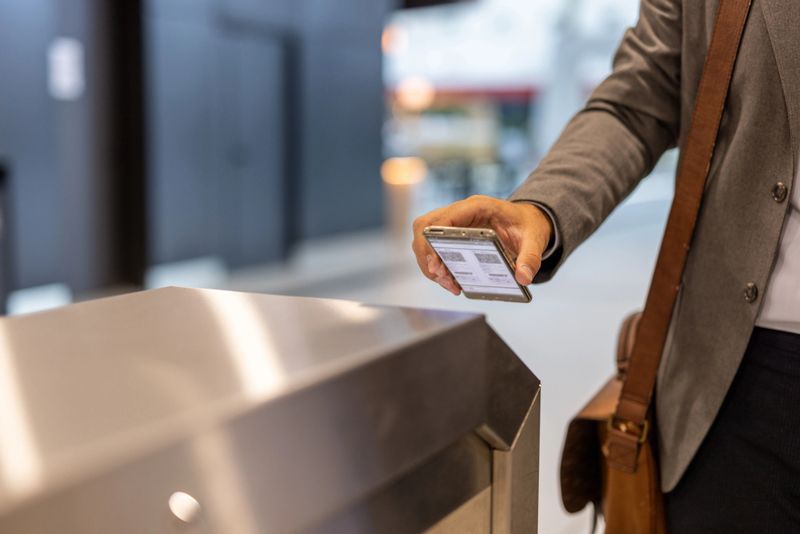 Businessman scanning a qr code with his smartphone at the entrance of an office building, enabling secure and convenient access to the corporate environment