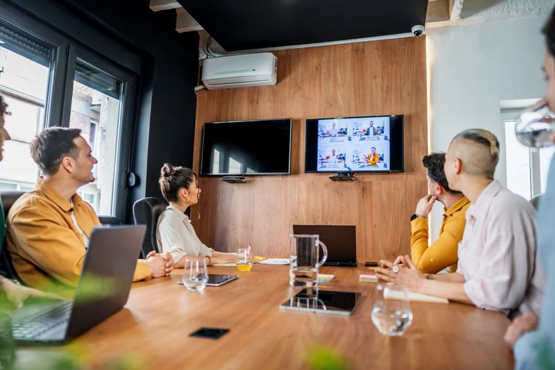 Business colleagues participating in a video conference within a sleek, modern boardroom, engaging in discussion and collaboration