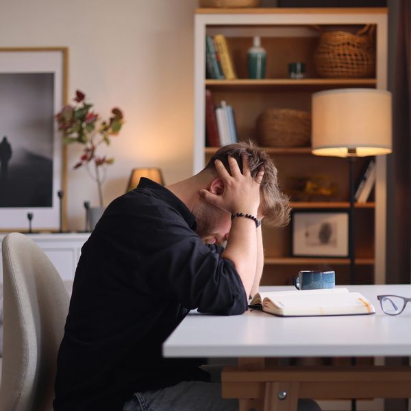 Man sitting at a desk with head in hands, appearing stressed or overwhelmed.