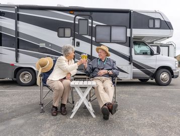 Elderly couple toasting drinks outside their RV.