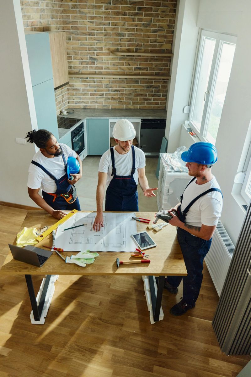 High angle view of group of workers communicating while working on housing plans at moving apartment.