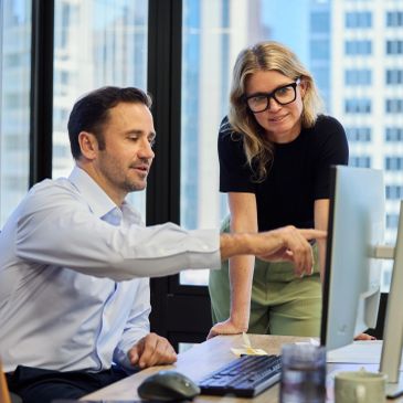 Coworkers discussing work at a computer.