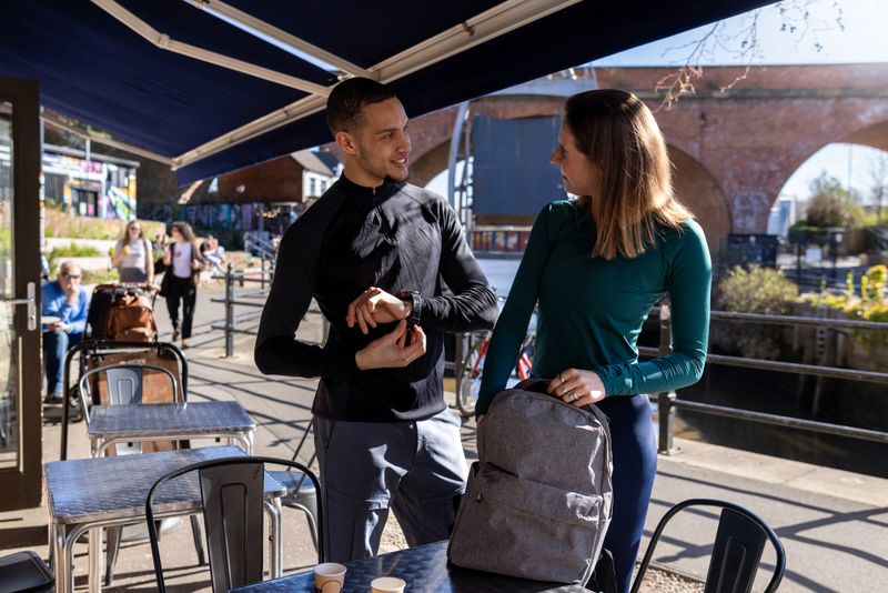 A wide shot of two people standing outside a cozy outdoor café, dressed in athletic gear and ready for a run. They share a light moment and a warm drink before setting off, capturing the balance of social connection and active lifestyle in an urban setting.

Videos are available similar to this scenario.