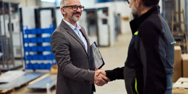 Two men shaking hands in a warehouse.