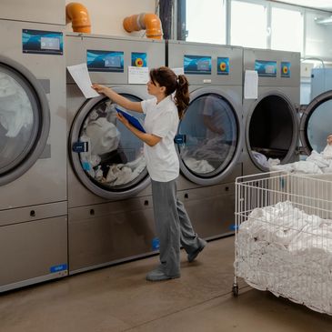 Laundry attendant cleaning clothes in a commercial laundry facility