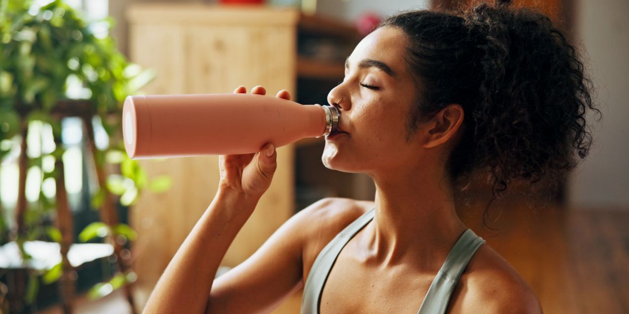 A woman getting hydrated, drinking water to stay healthy.