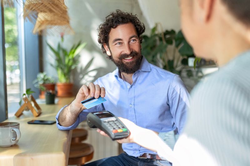 Businessman using credit card for contactless payment in cafe