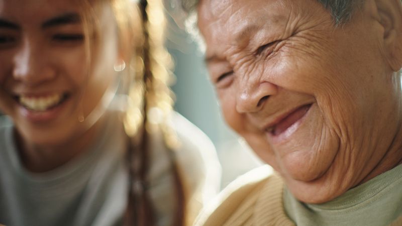 Asian senior woman and granddaughter enjoy playing game on a digital tablet at home.