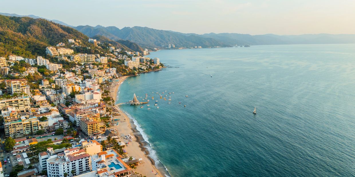 Coastal city with beach and mountains.