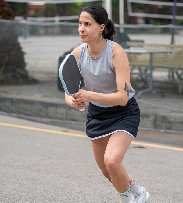 Woman playing pickleball, focused and ready to hit the ball.