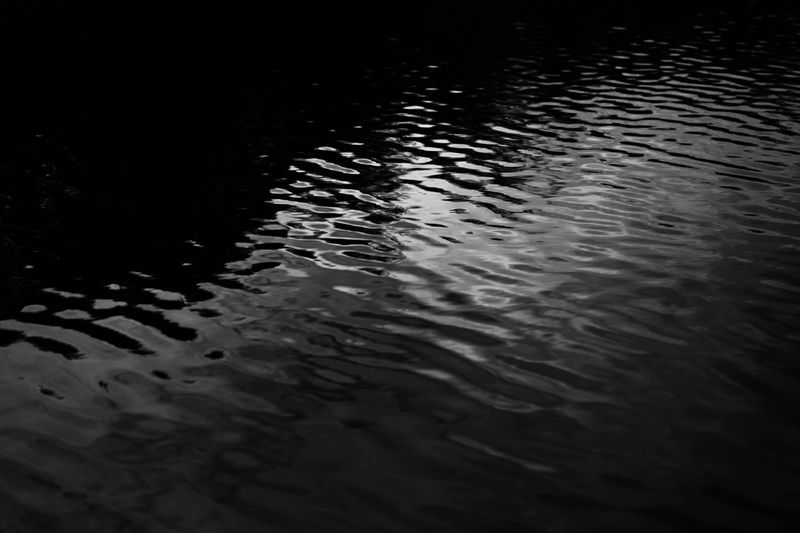 Black white dark gray silver water. Ripples. Reflection of light moonlight. Little waves. Gradient. Abstract. Contrast. Sea surface. Background with space for design.