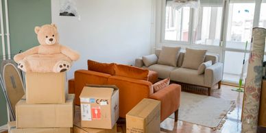 Moving boxes and a teddy bear in a living room.