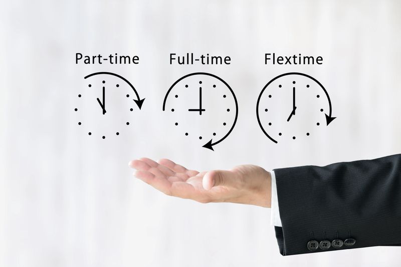 The hand of a businessman holding up clock icons representing various working hours
