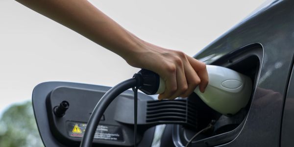 Hand plugging an electric charger into a car's charging port.