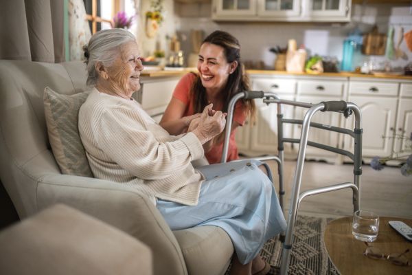 Elderly woman smiling with caregiver at home.