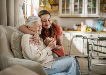 Young woman hugging elderly woman in cozy home.