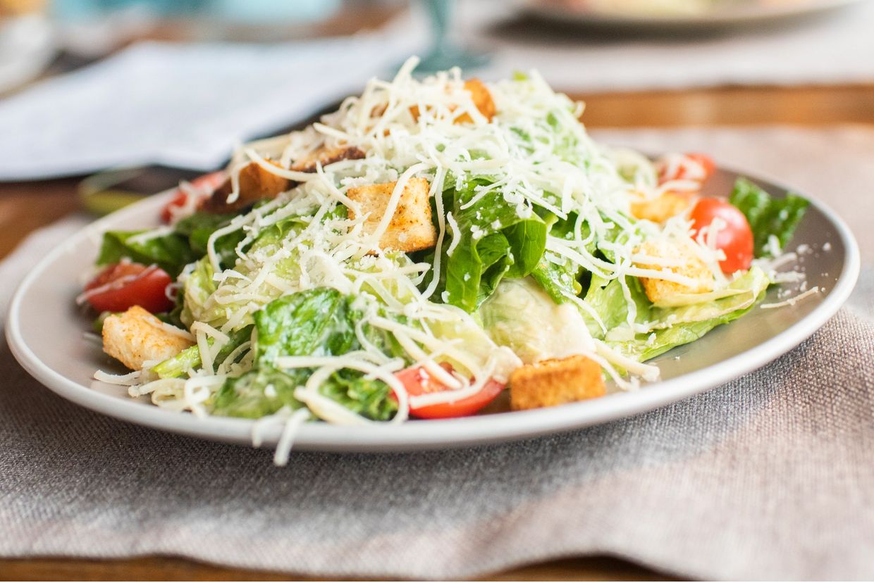 Fresh Caesar salad with lettuce, cherry tomatoes, croutons, and shredded cheese.