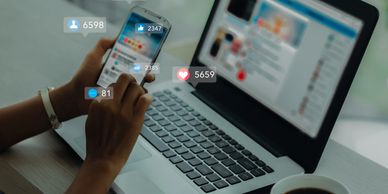 Person engaging with social media on phone and laptop, showing notifications.