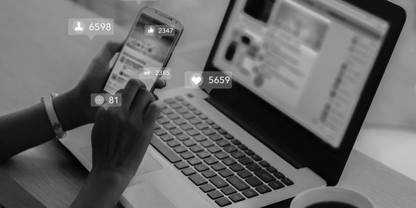 Person using smartphone and laptop with social media notifications.