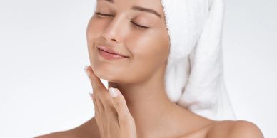 Young woman with towel wrapped on head smiling with eyes closed.