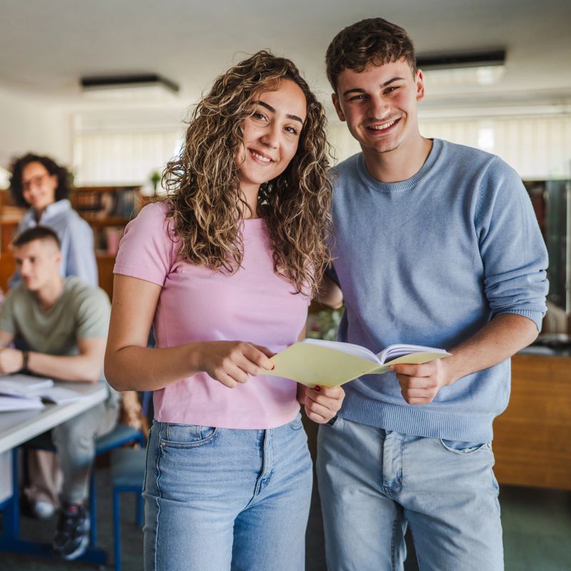 male and female student read notes from notebook prepare for class in the library