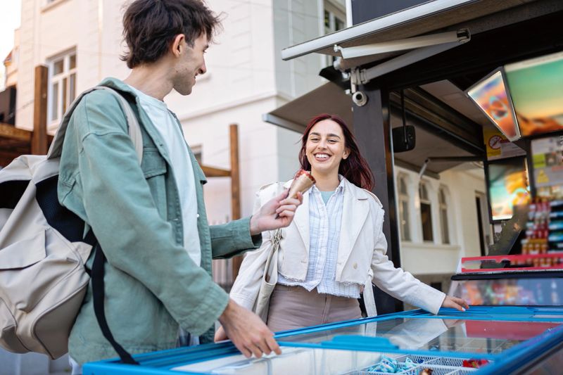 Two friends share smiles and ice cream while enjoying a relaxing summer afternoon outdoors.
