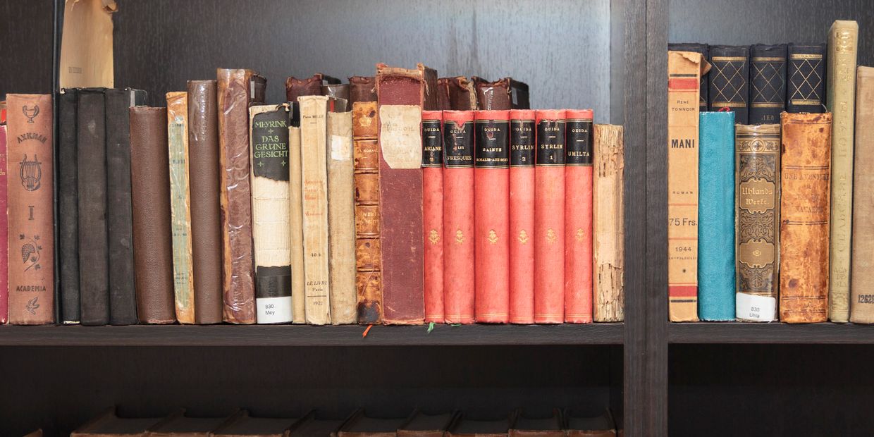A bookshelf filled with old, worn books of various colors and sizes.