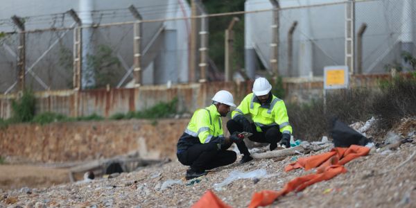 Two workers inspecting debris at a construction site.