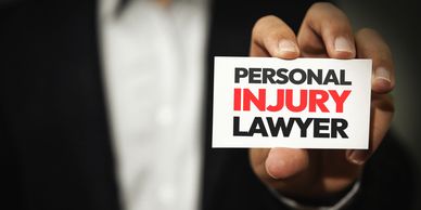 Person holding a card that says 'Personal Injury Lawyer'.