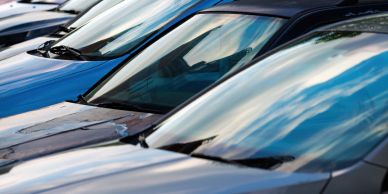 Close-up of parked car windshields reflecting the sky.