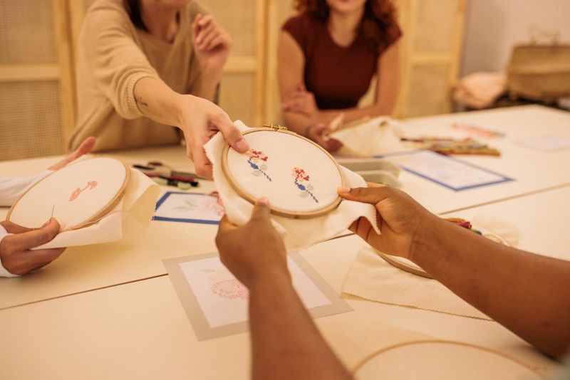 Small group of women engaged in learning embroidery techniques during a collaborative and relaxing crafting class in a modern workshop.