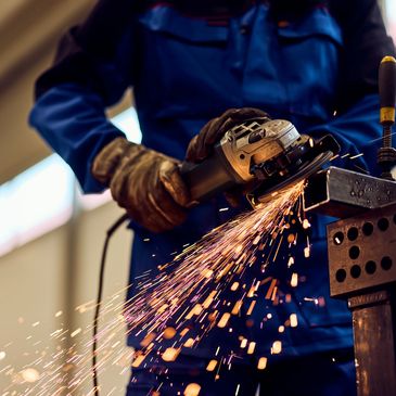 Worker grinding metal, sparks flying from the tool.