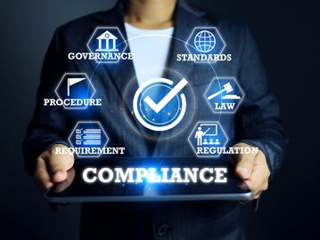 Businessman holding a tablet displaying compliance concepts with icons and text.