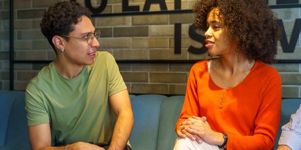 Two people engaged in a friendly conversation on a couch.