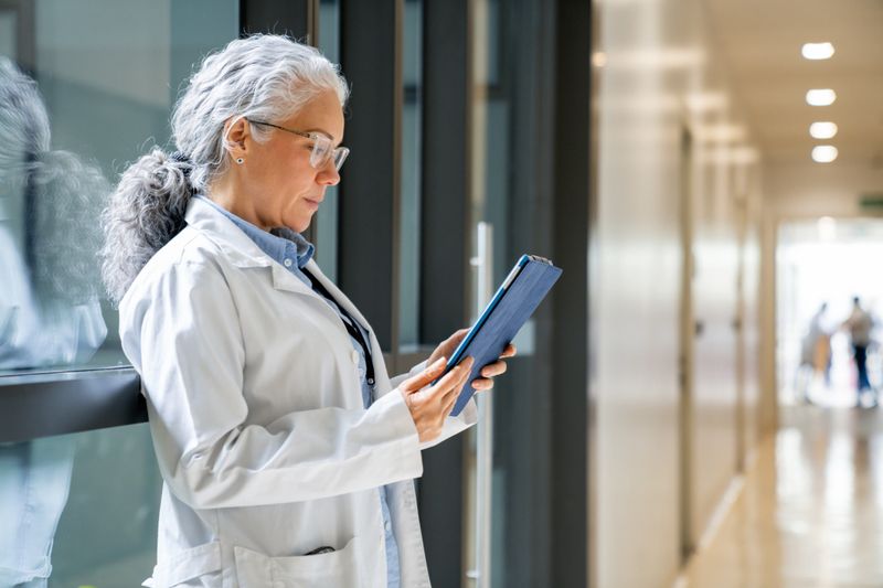 Latin American female doctor reading a medical chart using a digital tablet at the hospital - healthcare and medicine concepts