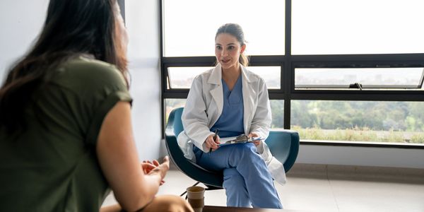 A doctor attentively listens to a patient during a consultation in a bright room.