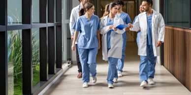 Group of healthcare professionals walking and discussing in a hospital corridor.