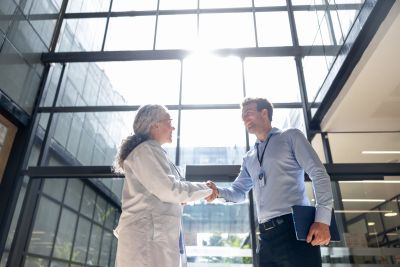 Two professionals shaking hands in a modern office building.