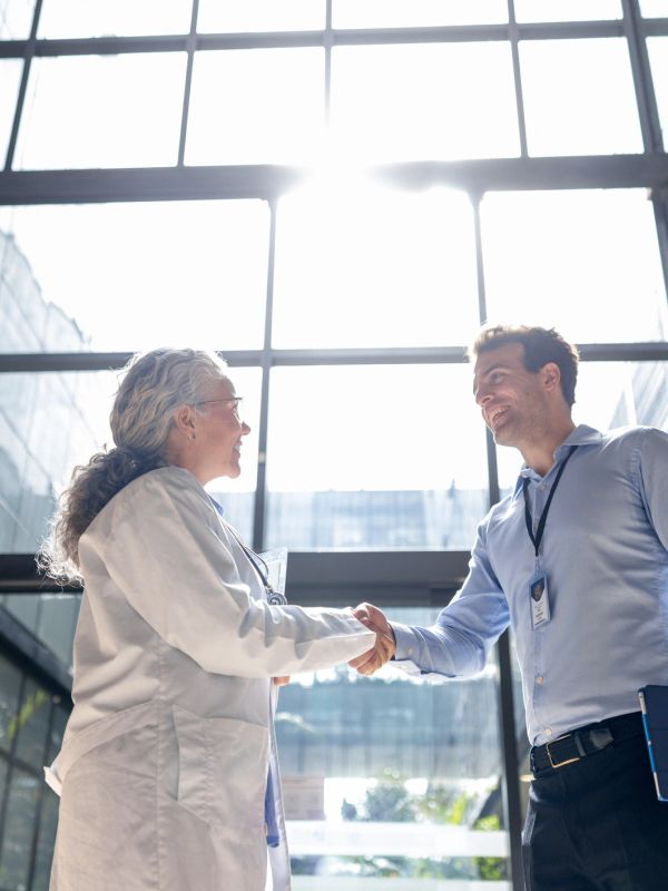 Doctor and businessman shaking hands in a bright modern building.