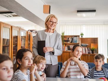 Teacher engaging with attentive students in a classroom setting.