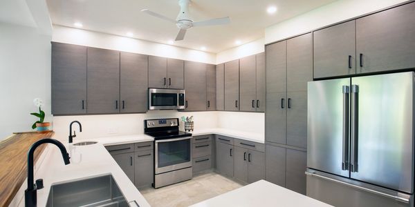 Modern kitchen with gray cabinets, stainless steel appliances, and white countertops.
