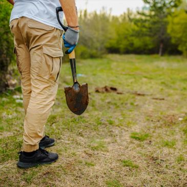 Person holding a shovel in a grassy area.