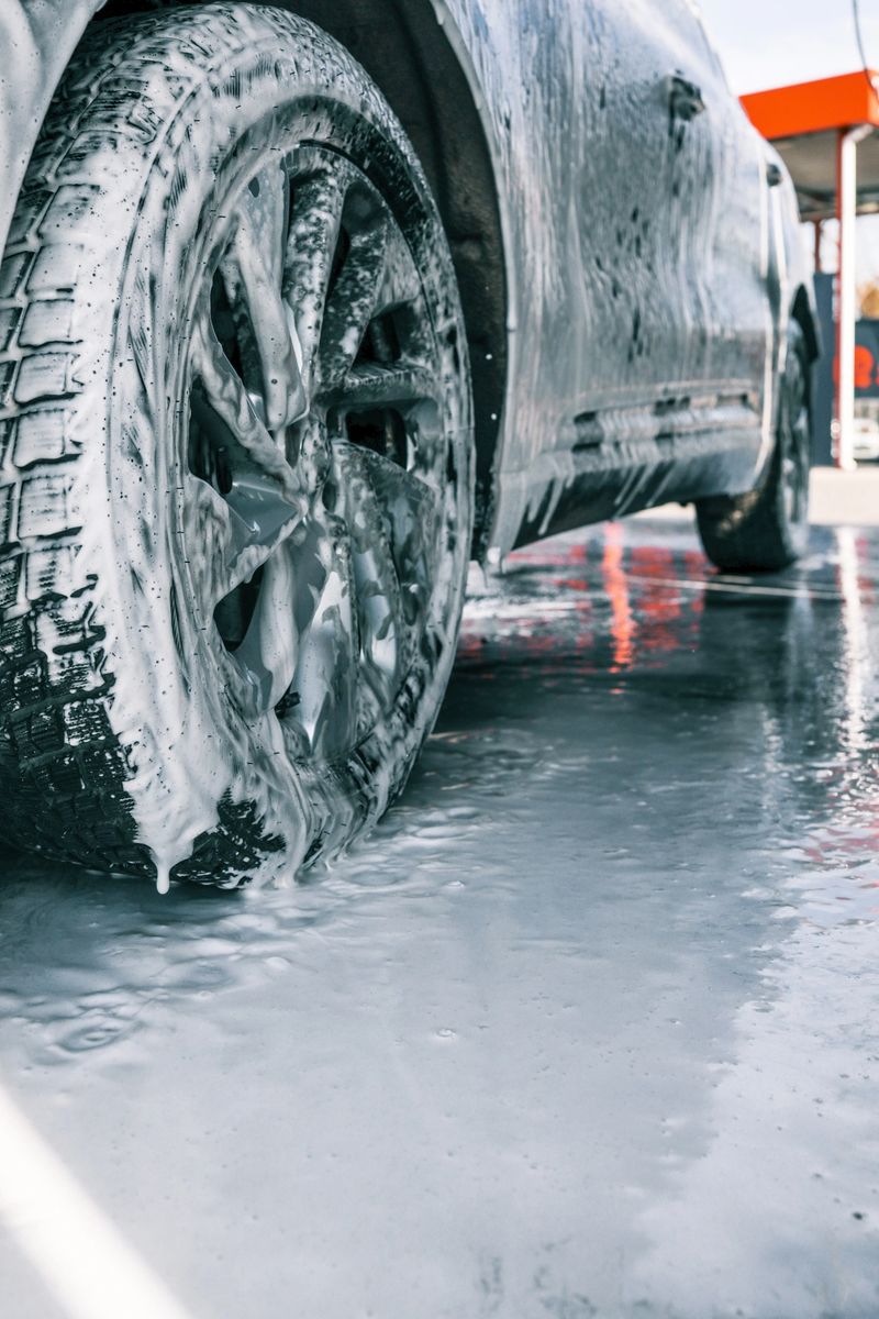 Close-up of a car wheel covered in foam during washing at a self-service car wash, modern cleaning process.